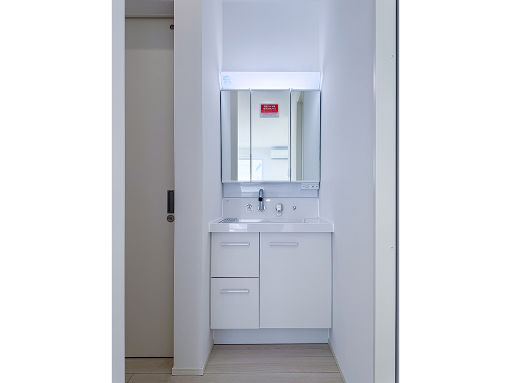 【洗面台】リクシル製｜曇り止めコート、三面鏡裏・キャビネット収納つき。玄関やトイレからのアクセスも良好です。